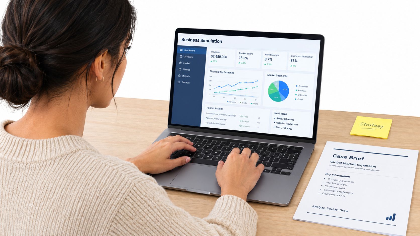 A woman working on a laptop displaying business simulation software at a desk with strategy documents.