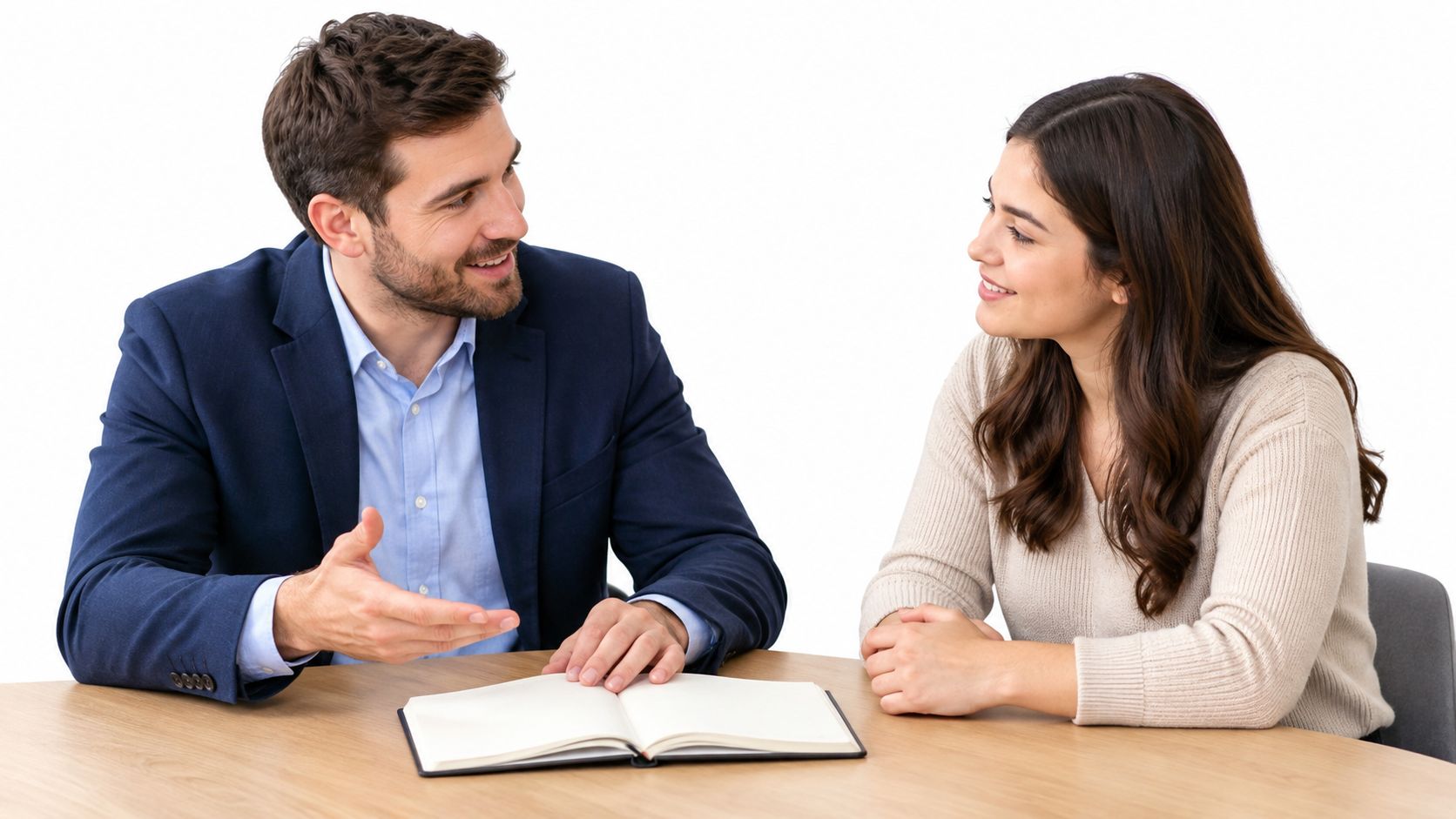 A professional man and woman having a friendly conversation while sitting at a table with an open notebook.